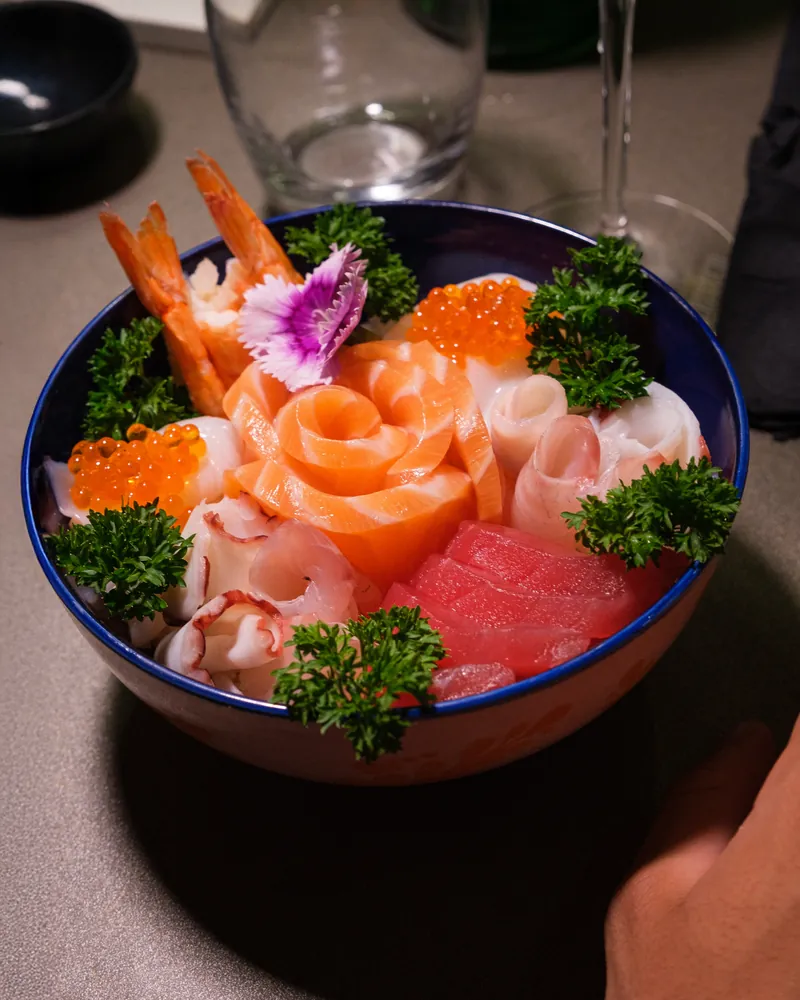 Ciotola con sashimi, crostacei e uova sulla tavola davanti a un'ospite