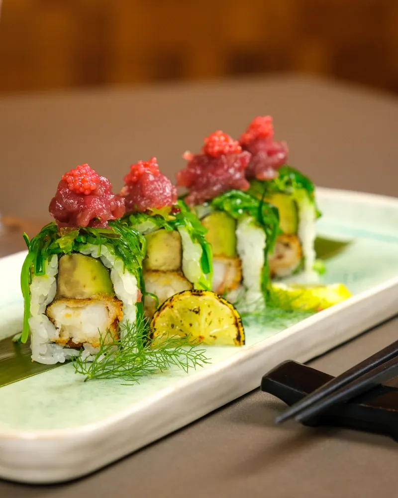 Uramaki con verdure, copertura verde e piccoli ciuffi di tartare