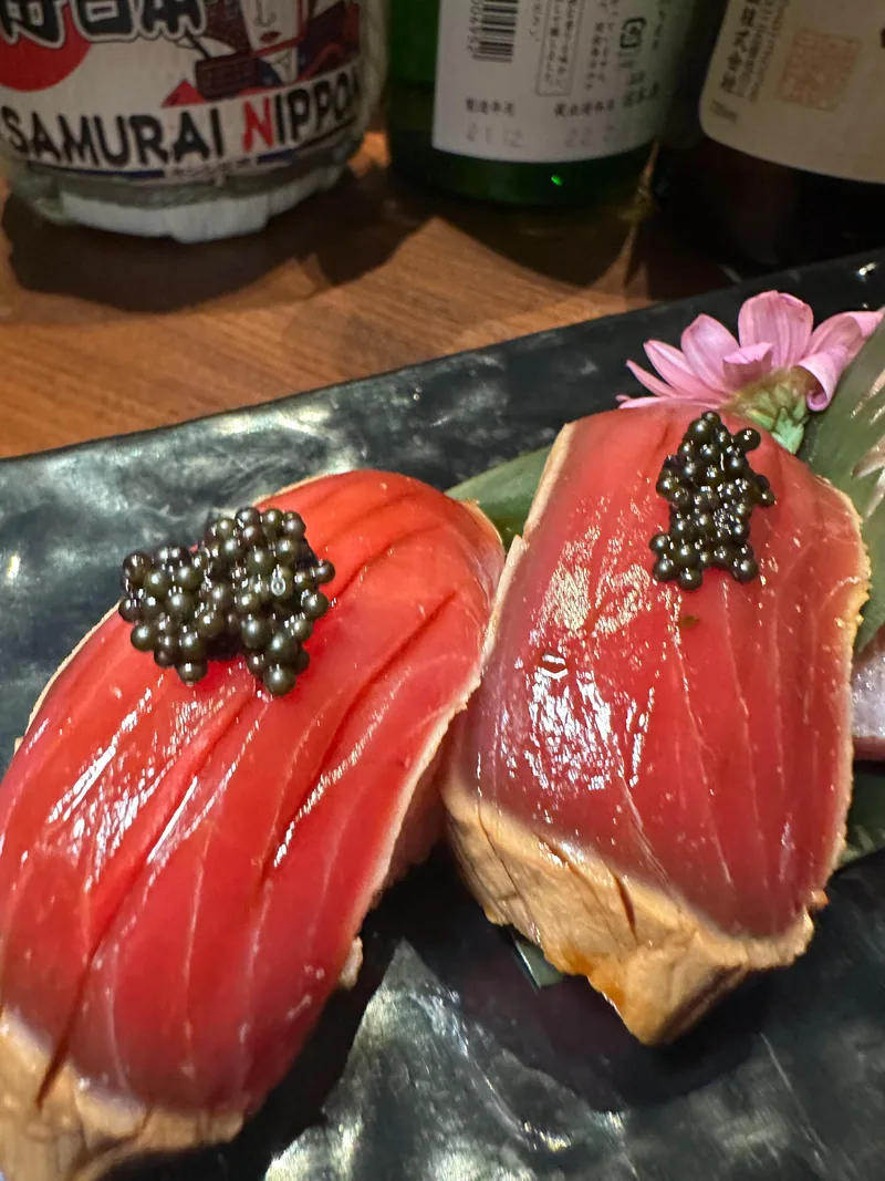 Due nigiri di tonno con uova nere su piatto scuro