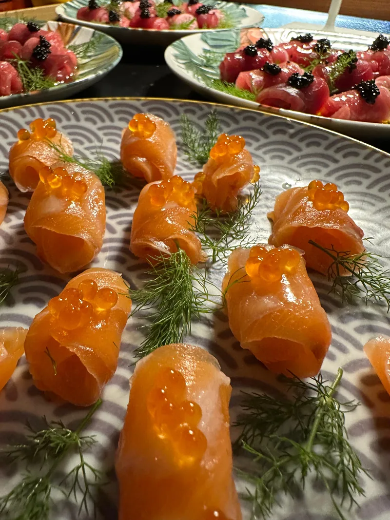 Rotolini di salmone con uova arancioni su un piatto decorato